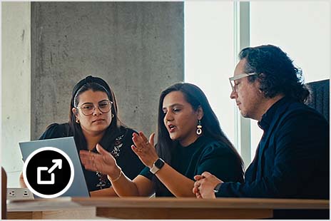 Two women and a man collaborating at a laptop computer