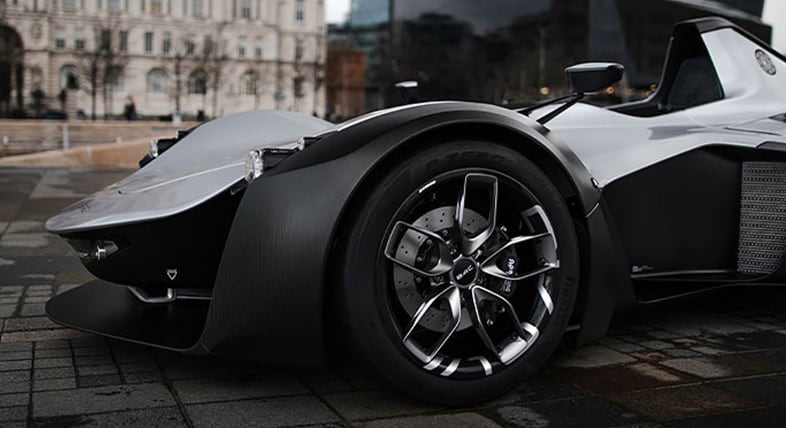 Bild eines Hochleistungsreifens an einem futuristisch anmutenden eleganten, schwarzen Sportwagen 