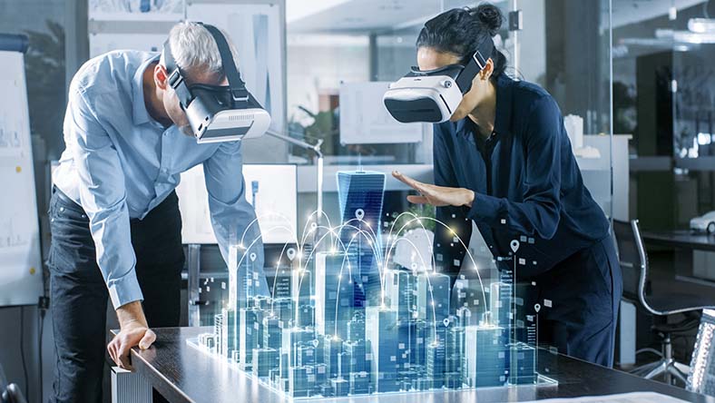 Male and female architects wearing AR headsets work with 3D city model projected on the table in front of them