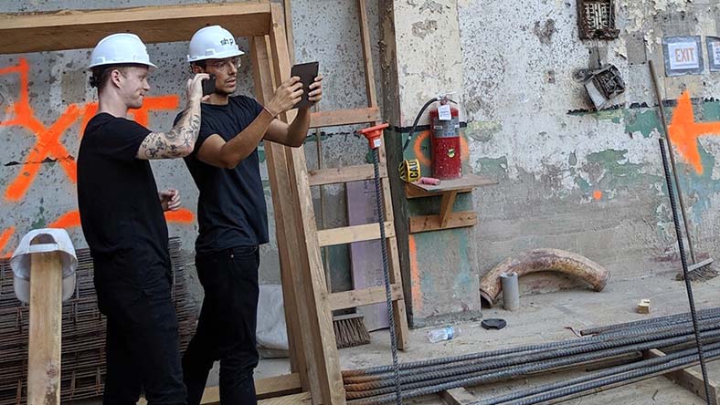 Two SHoP architects use an AR app to overlay a building model onto a jobsite in industrial outdoor setting