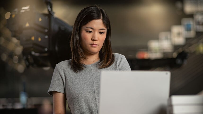 Woman in gray shirt studying computer screen 