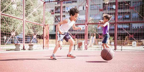 A boy and a girl play on a basketball court