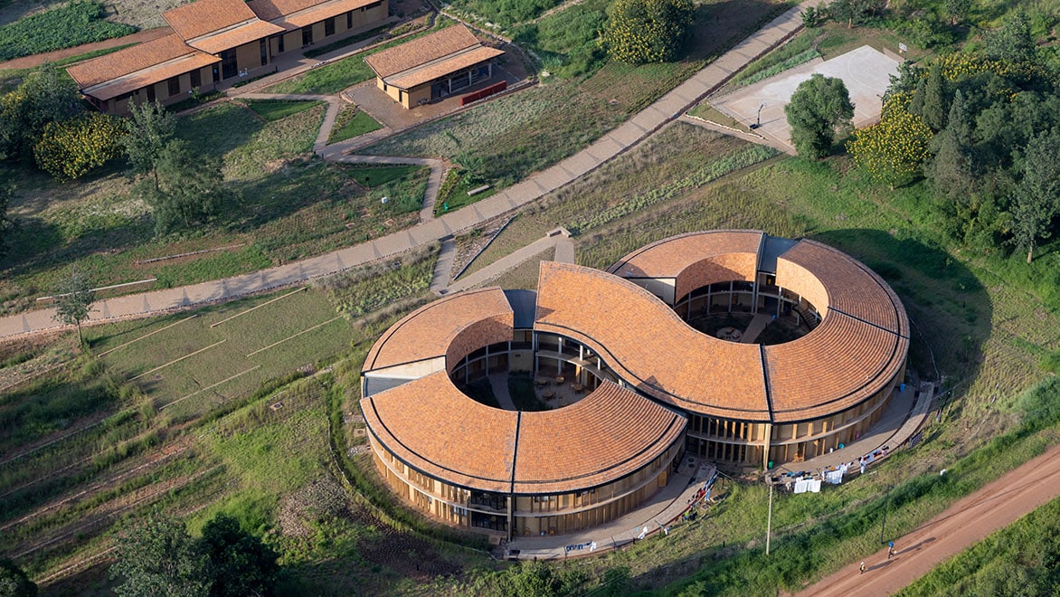 Aerial view of MASS Design's Rwanda Institute for Conservation Agriculture (RICA); building shaped like an infinity symbol surrounded by rural land.