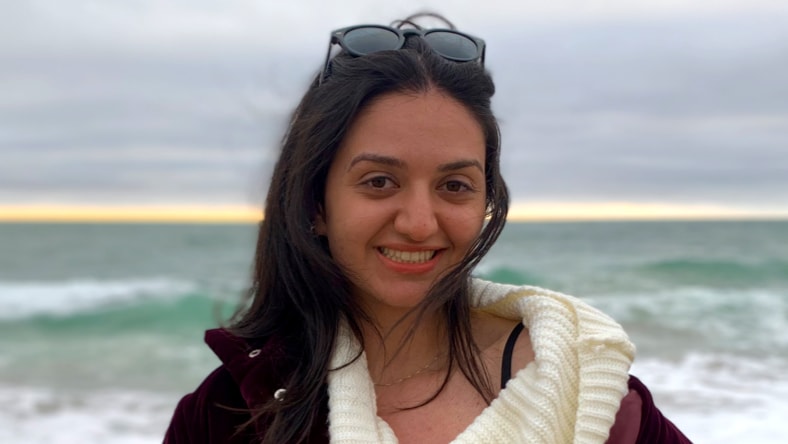 Headshot image of Maryam Nassir, Controls Engineer, Heirloom, standing on a beach, smiling, wearing sunglasses on her head.