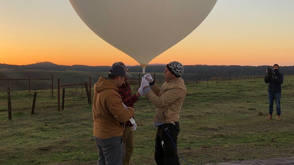 Team launches a weather tracking balloon in a field