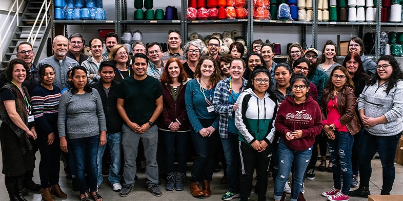 Company photo of ~50 smiling employees in outdoor setting