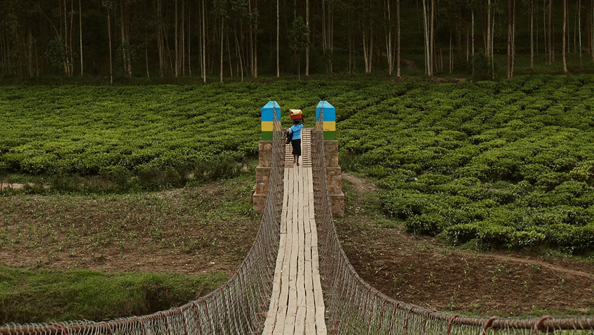 Person crosses a trailbridge carrying water