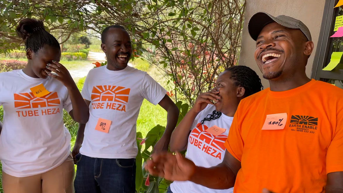 A group of EarthEnable employees wearing orange EarthEnable shirts