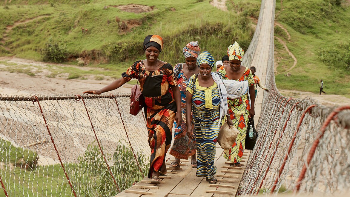 A group of women cross a trail bridge in Rwanda
